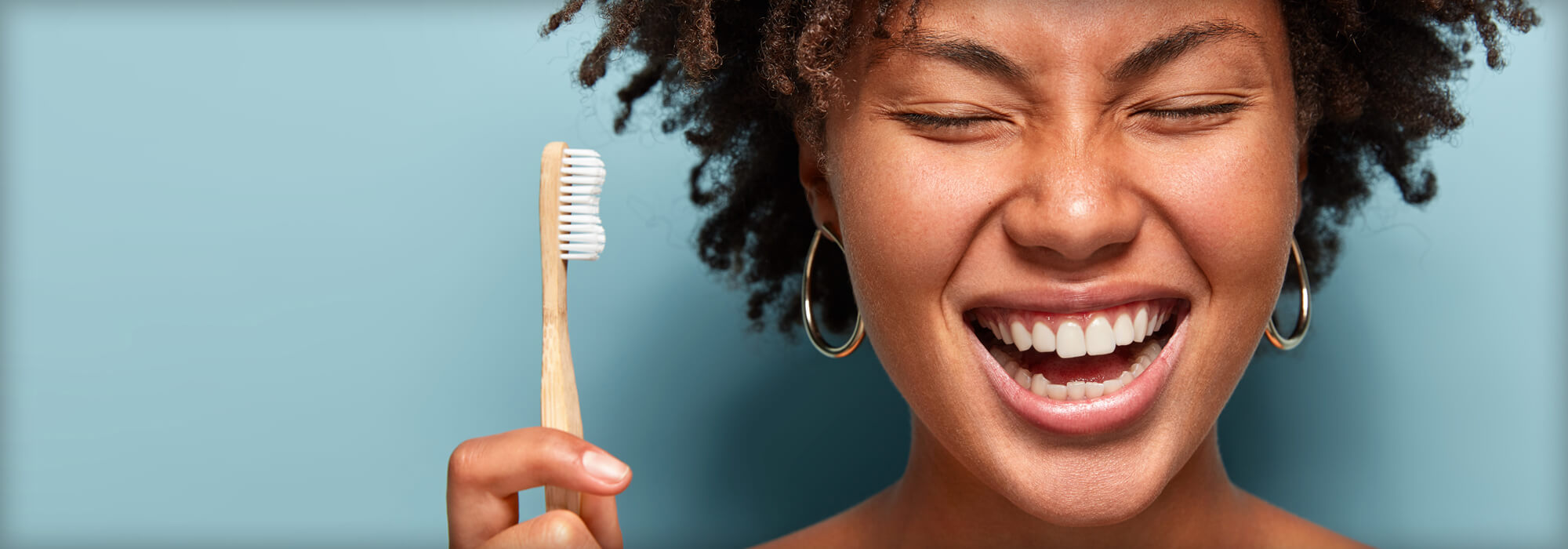 dentalhealth Woman holding a natural wood toothbrush.